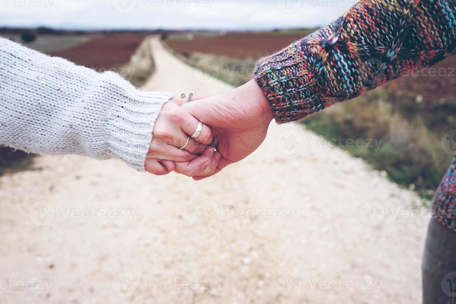 close de um jovem casal de mãos dadas, mostrando seu noivado em uma viagem de aventura em um caminho ao ar livre no campo foto