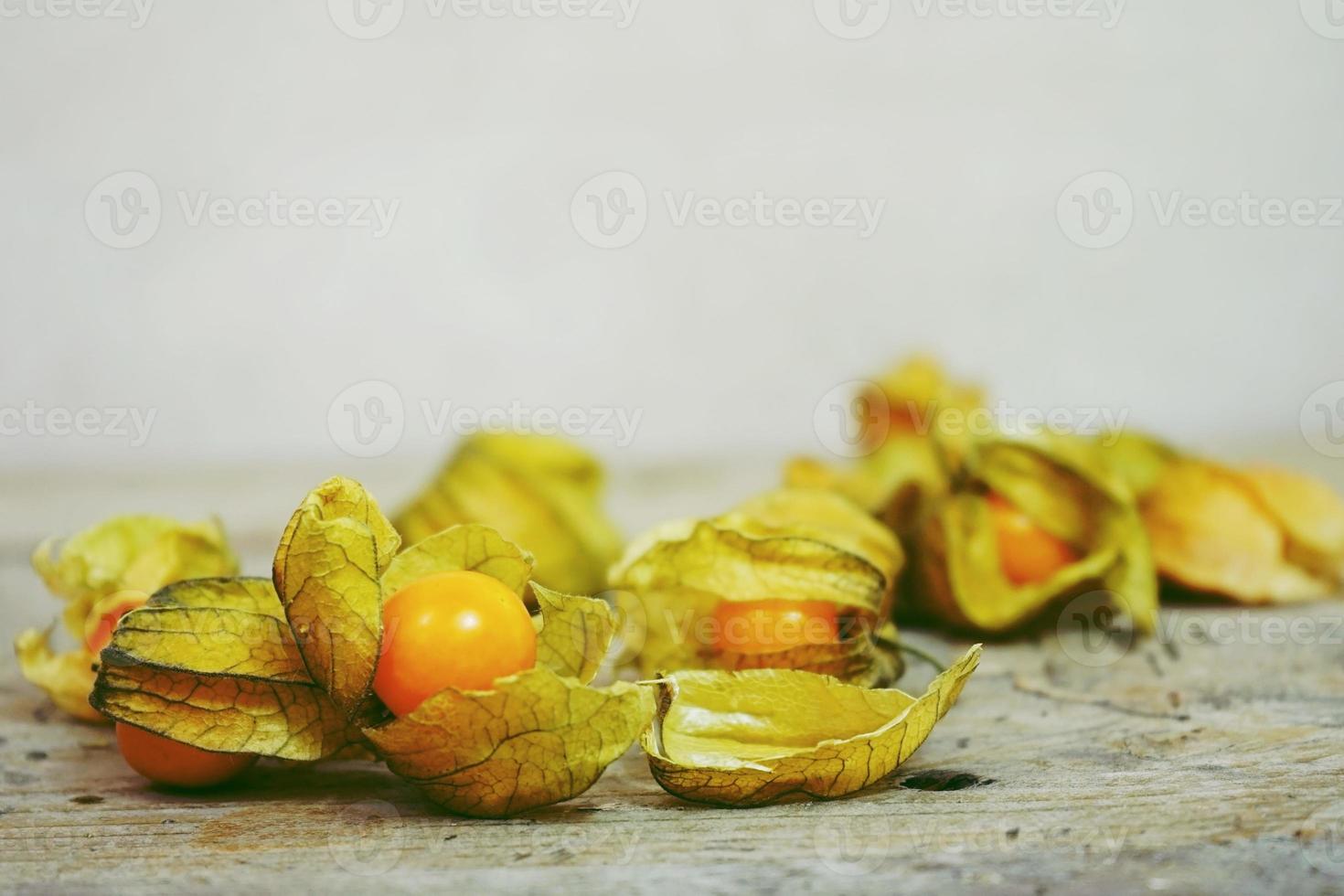 Belo e elegante close-up macro de uma fruta saborosa muito laranja chamada Physalis do Peru, América do Sul, sobre mesas de madeira foto