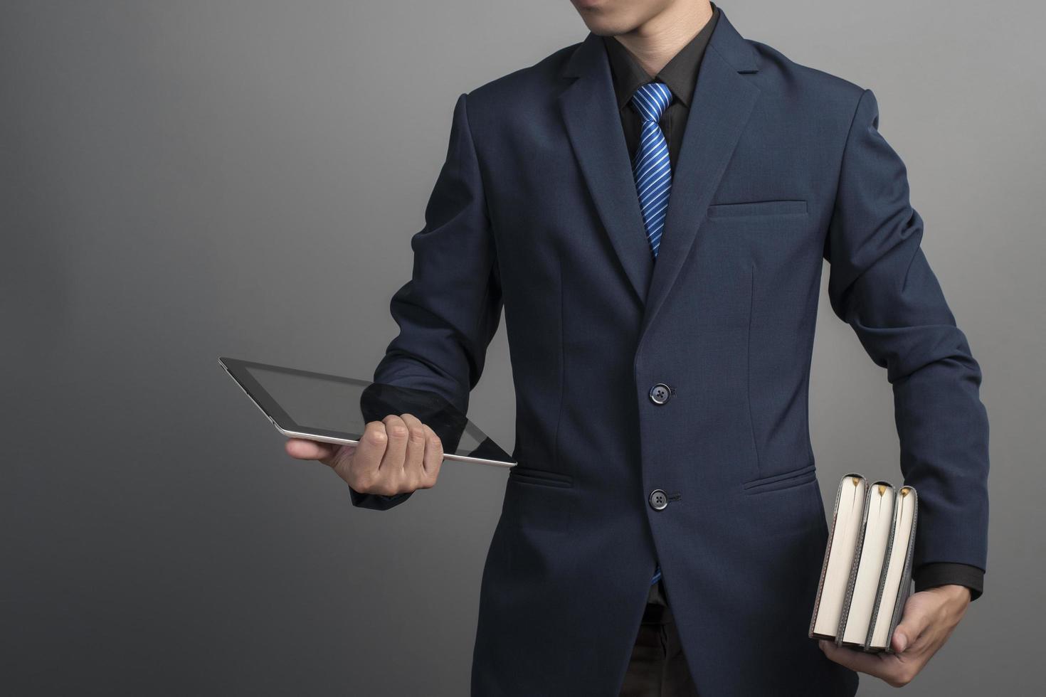 close-up do empresário em um terno azul segurando livros sobre fundo cinza foto