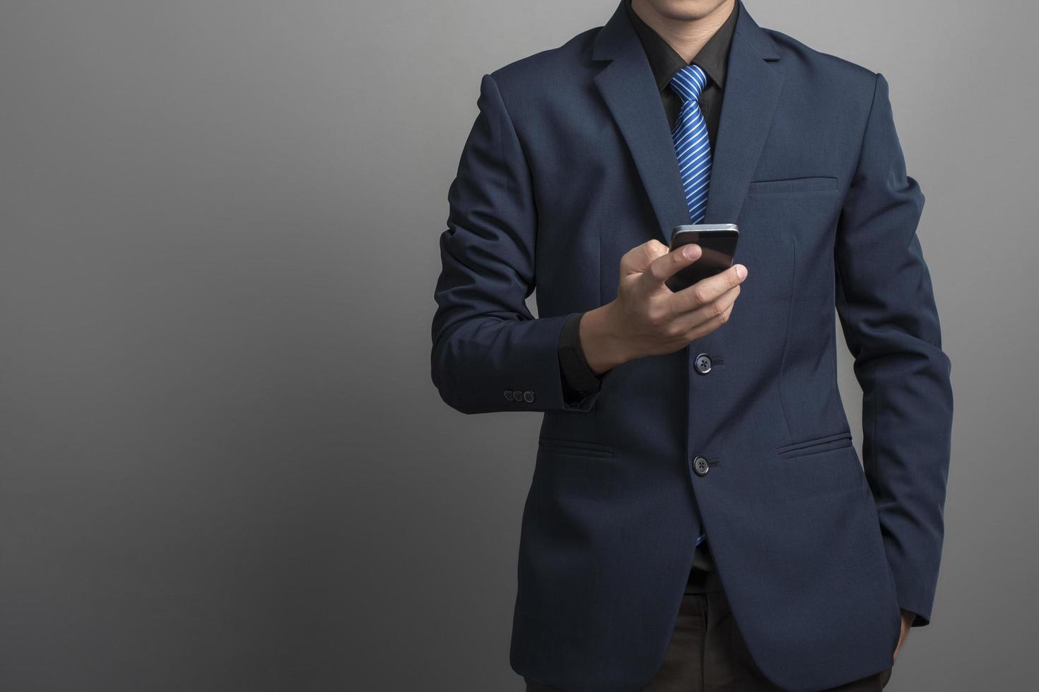 close-up do empresário de terno azul usando smartphone em fundo cinza foto