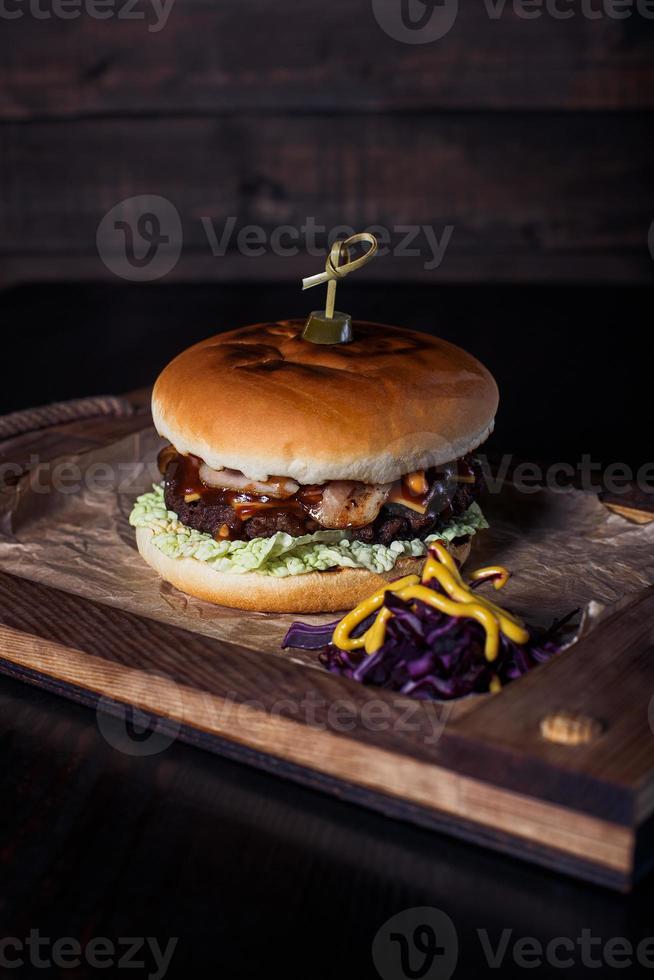 cheeseburguer em uma bandeja de madeira em um restaurante, em um fundo escuro foto