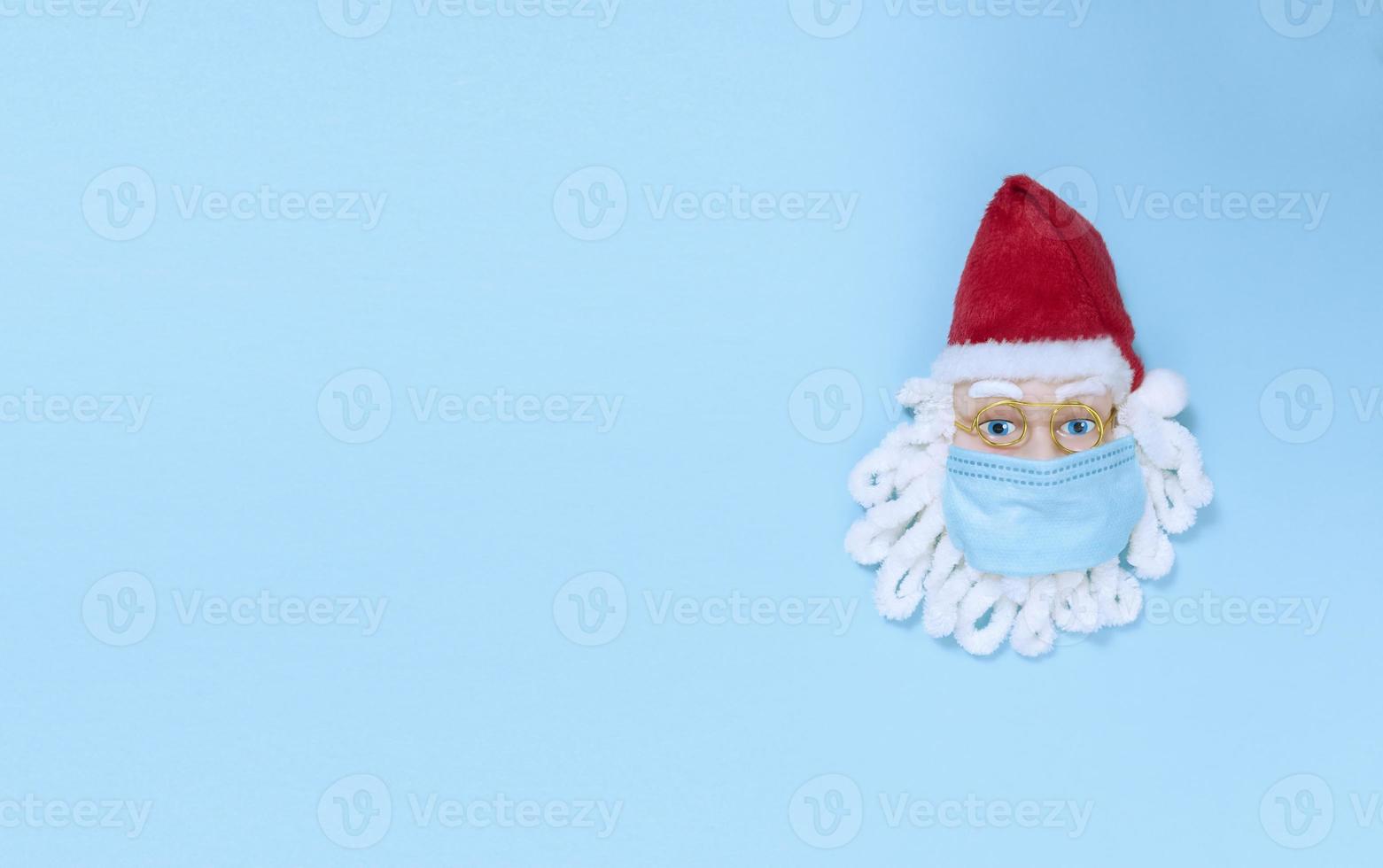 Papai Noel em máscara médica em um papel azul. lay flat simples com espaço de cópia. foto