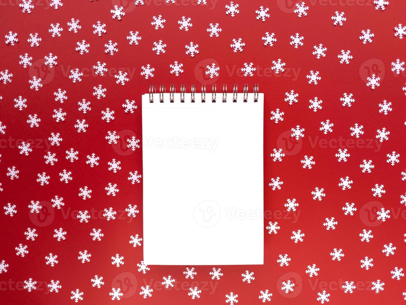 folha em branco do caderno com flocos de neve brancos espalhados sobre fundo vermelho. conceito educacional. lay flat simples com espaço de cópia. foto. foto