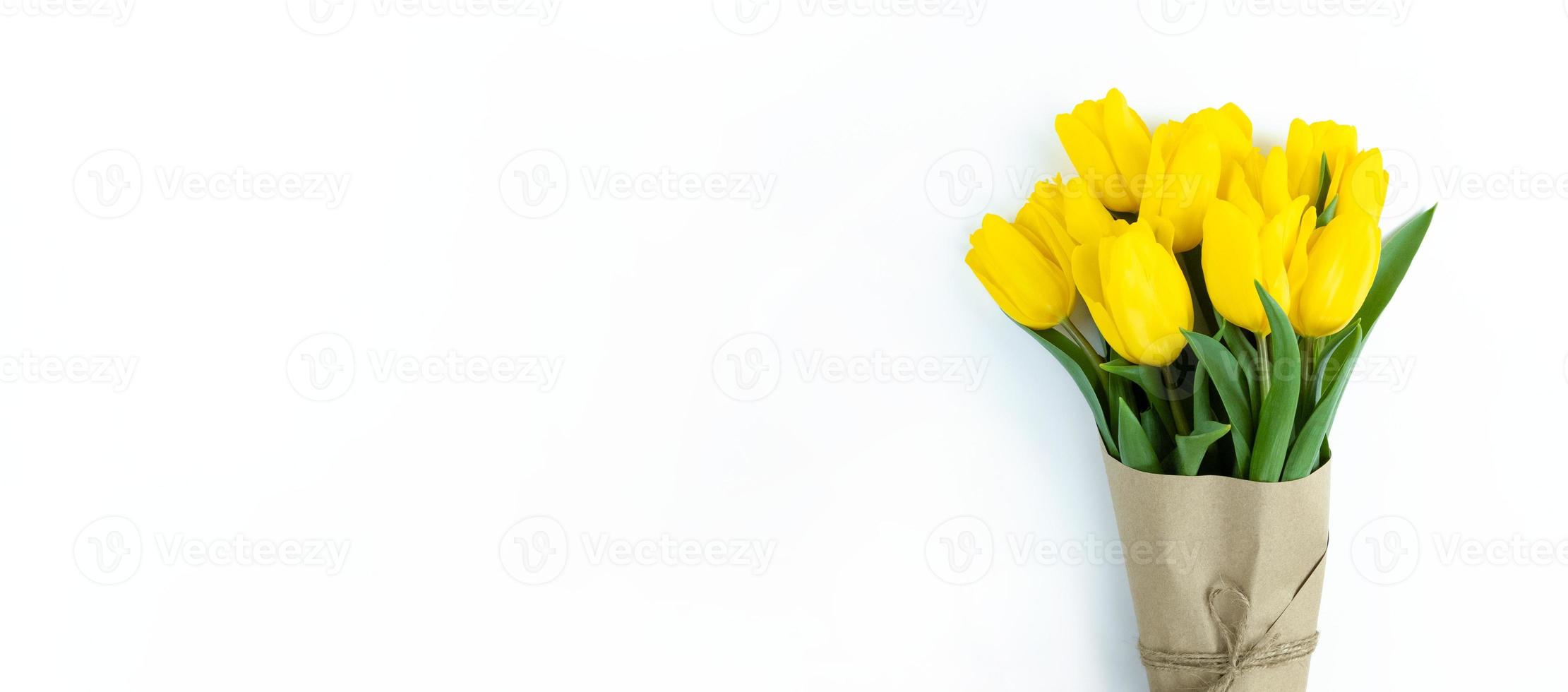 buquê de tulipas amarelas embrulhadas em papel ofício em fundo branco com espaço de cópia. foto
