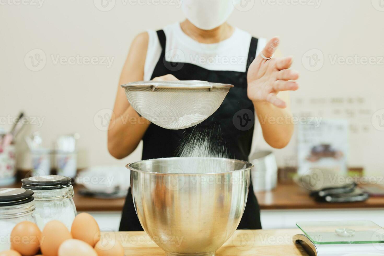 mulher padeiro peneirar farinha para dentro mistura tigela. foto