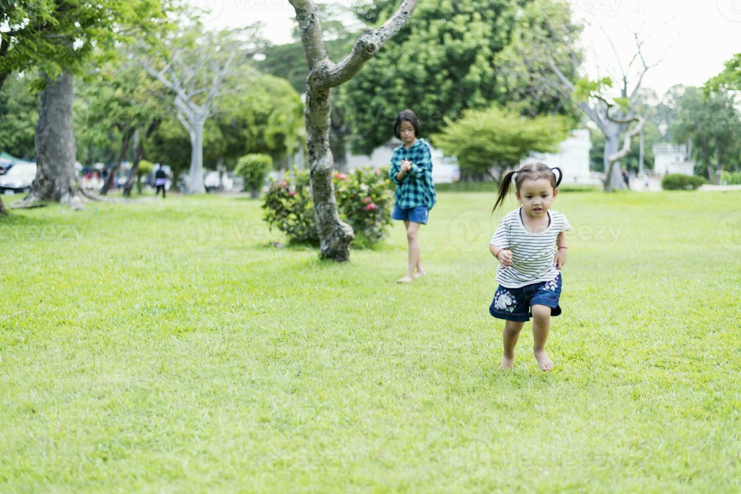 feliz sudeste ásia meninas jogando ao ar livre dentro a Primavera parque. ásia crianças jogando dentro a jardim verão período de férias. foto