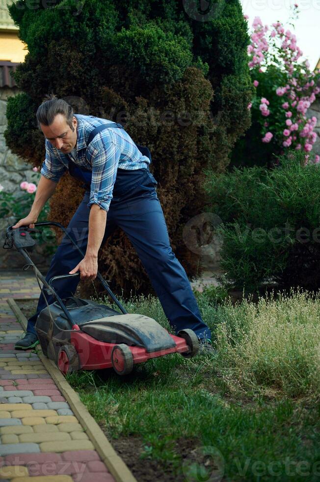 profissional paisagista usando elétrico gramado cortador de grama, corte Relva com moderno jardinagem equipamento. paisagismo indústria foto