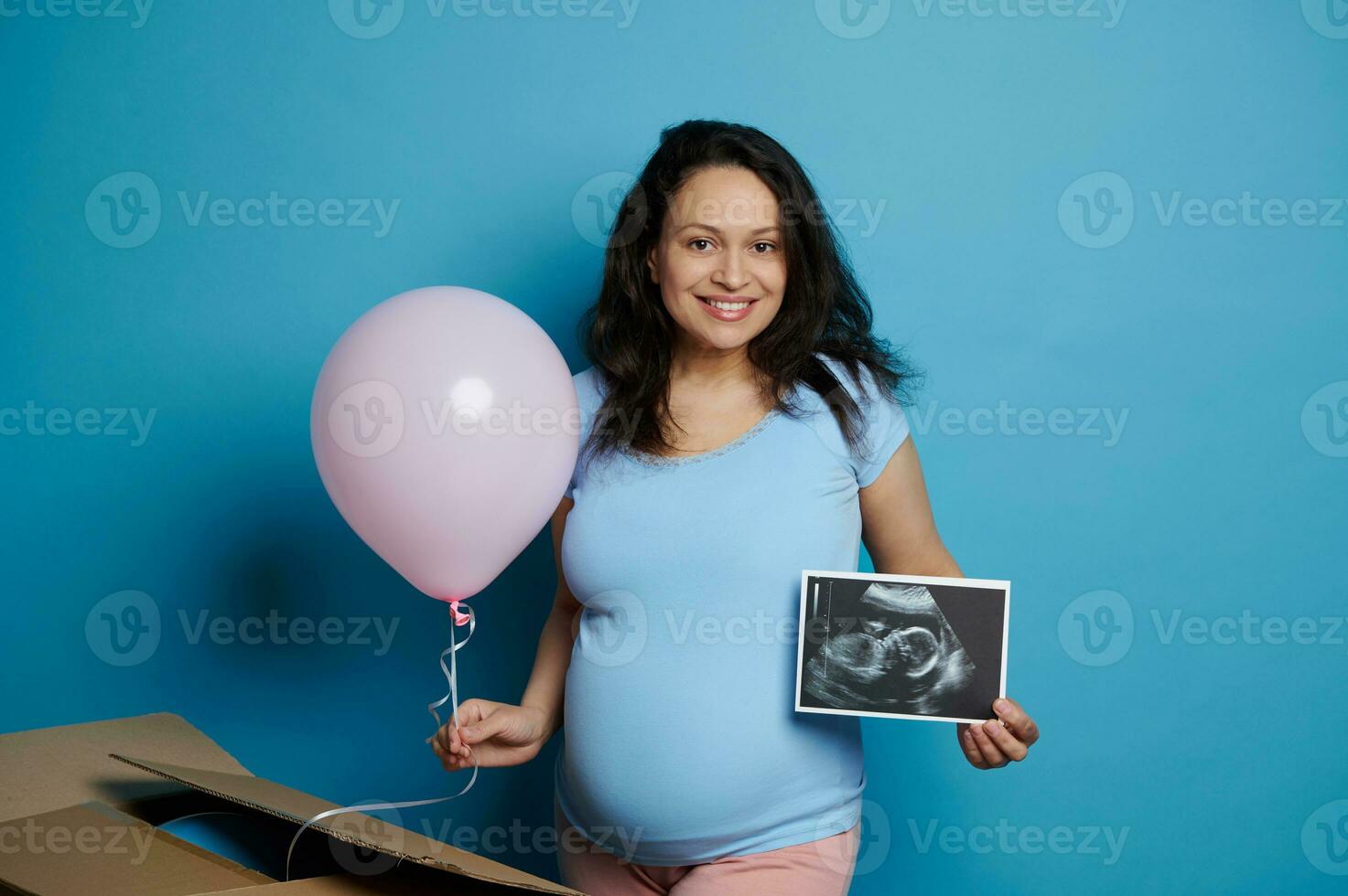 grávida mulher esperando uma bebê garota, sorrisos alegremente, posando com Rosa balão e ultrassom imagem, isolado em Rosa foto