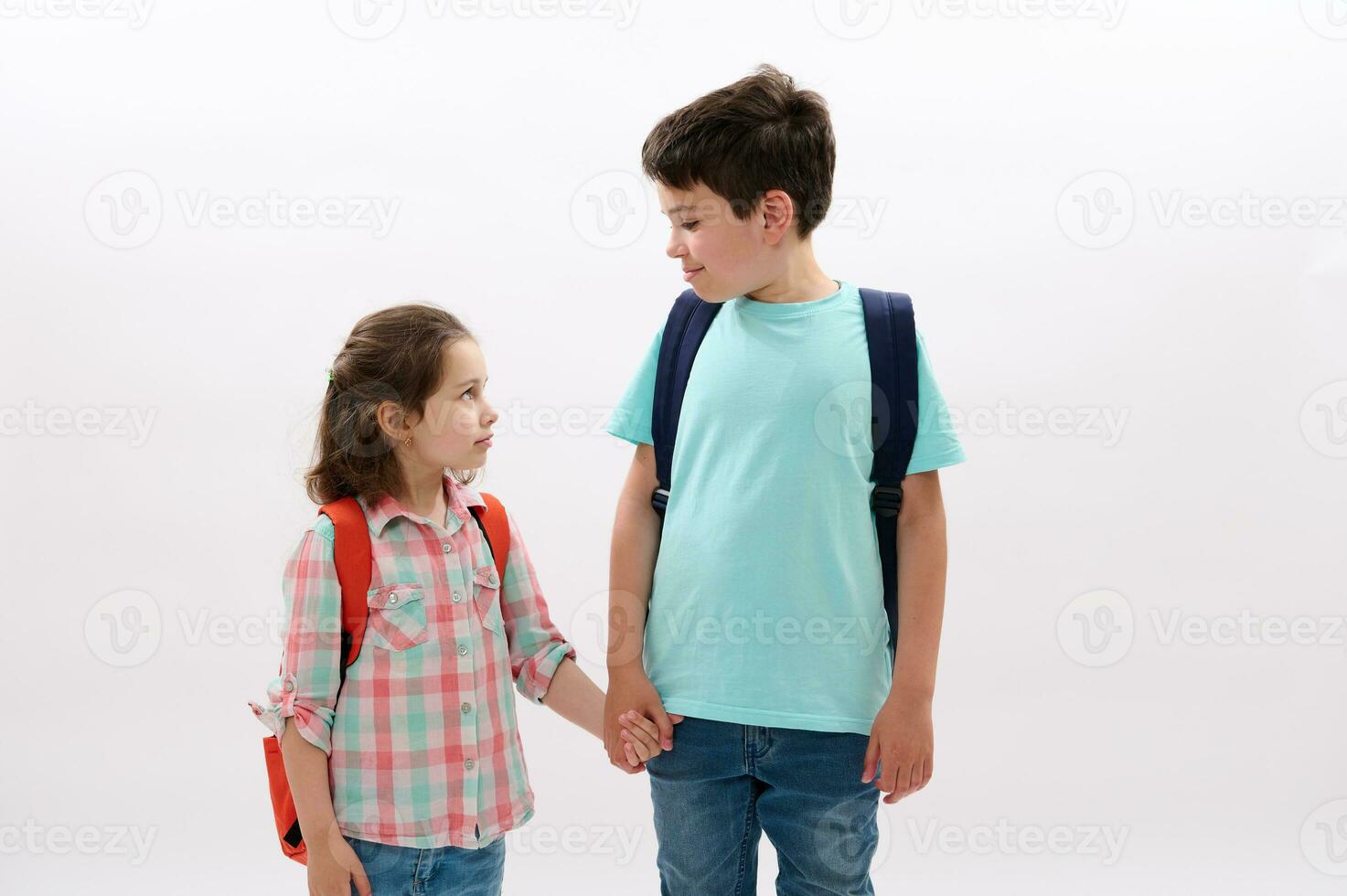 feliz escolares, irmão e irmã segurando mãos, indo para a escola, sorrir olhando às cada outro, isolado em branco foto