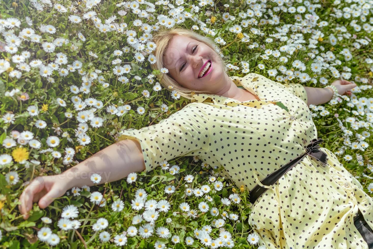 menina loira gosta de ficar deitada em um campo cheio de flores foto