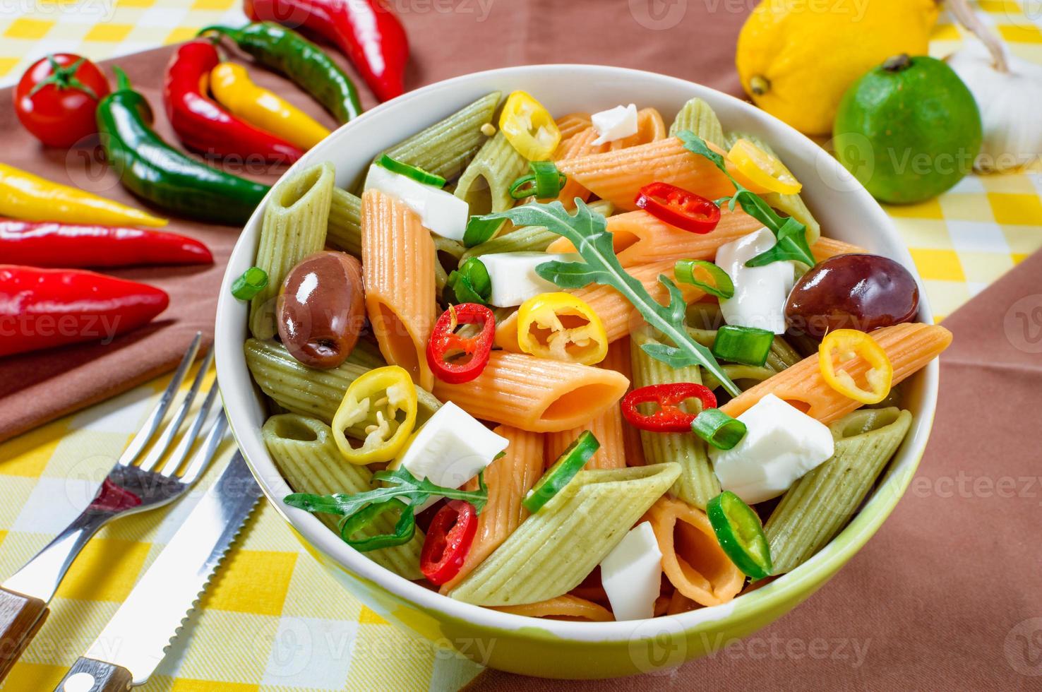 Salada de macarrão com tomate, rúcula, pepino, pimentão, pimenta, azeitonas pretas e verdes e queijo feta. vista do topo. foto