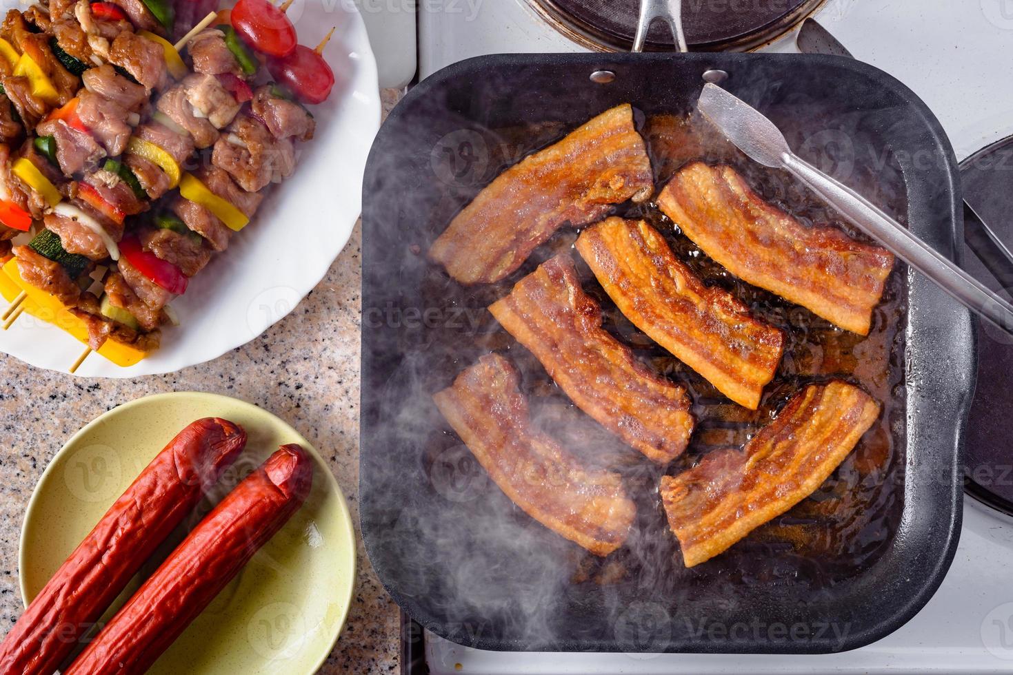 bacon grelhado. salsicha e espetos de porco crus prontos para grelhar. foto