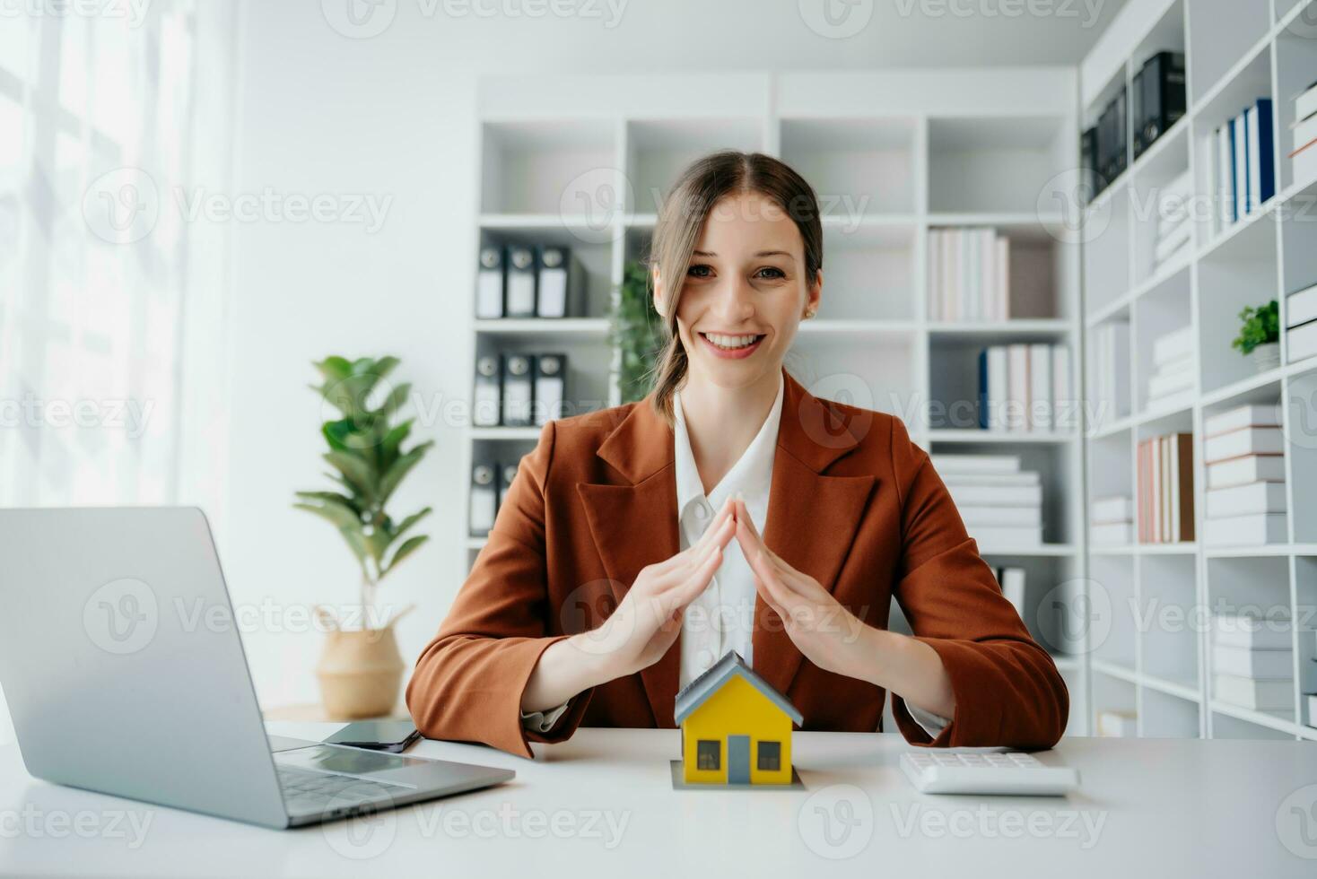 agente imobiliário feminino usa as mãos para proteger o telhado vermelho para o conceito de investimento imobiliário sobre comércio de casas, compra na mesa do escritório foto