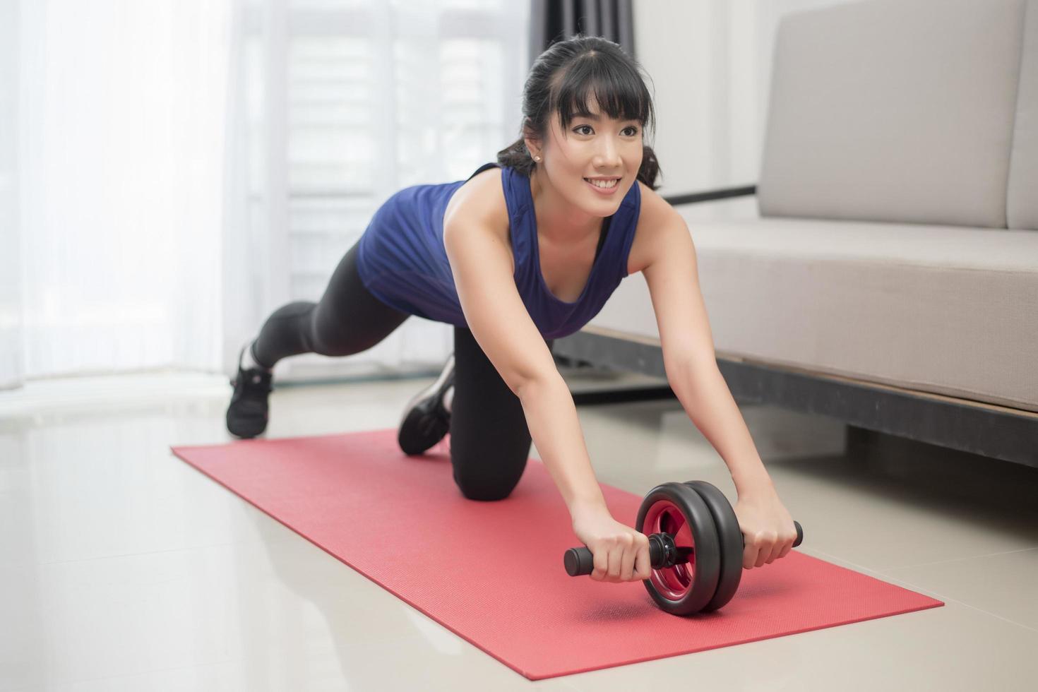 linda mulher desportiva fazendo exercícios abdominais com roda em casa foto