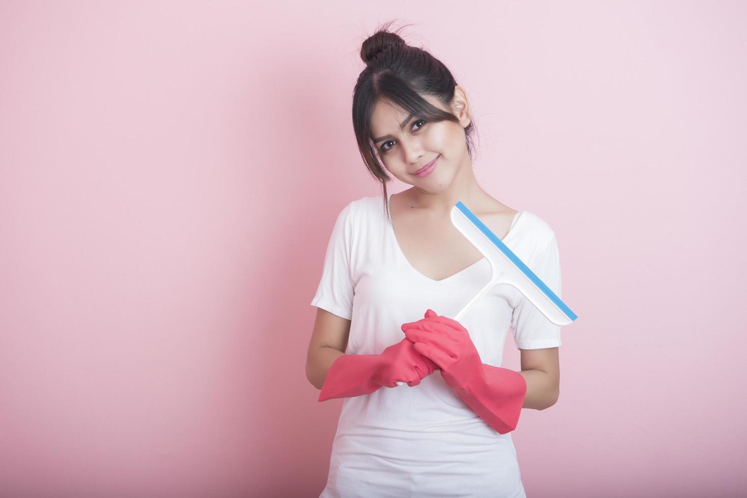 linda dona de casa asiática sorrindo em fundo rosa foto