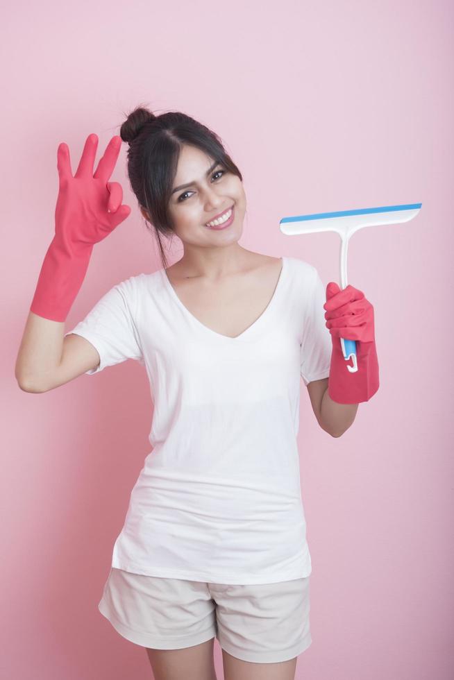 linda dona de casa asiática sorrindo em fundo rosa foto