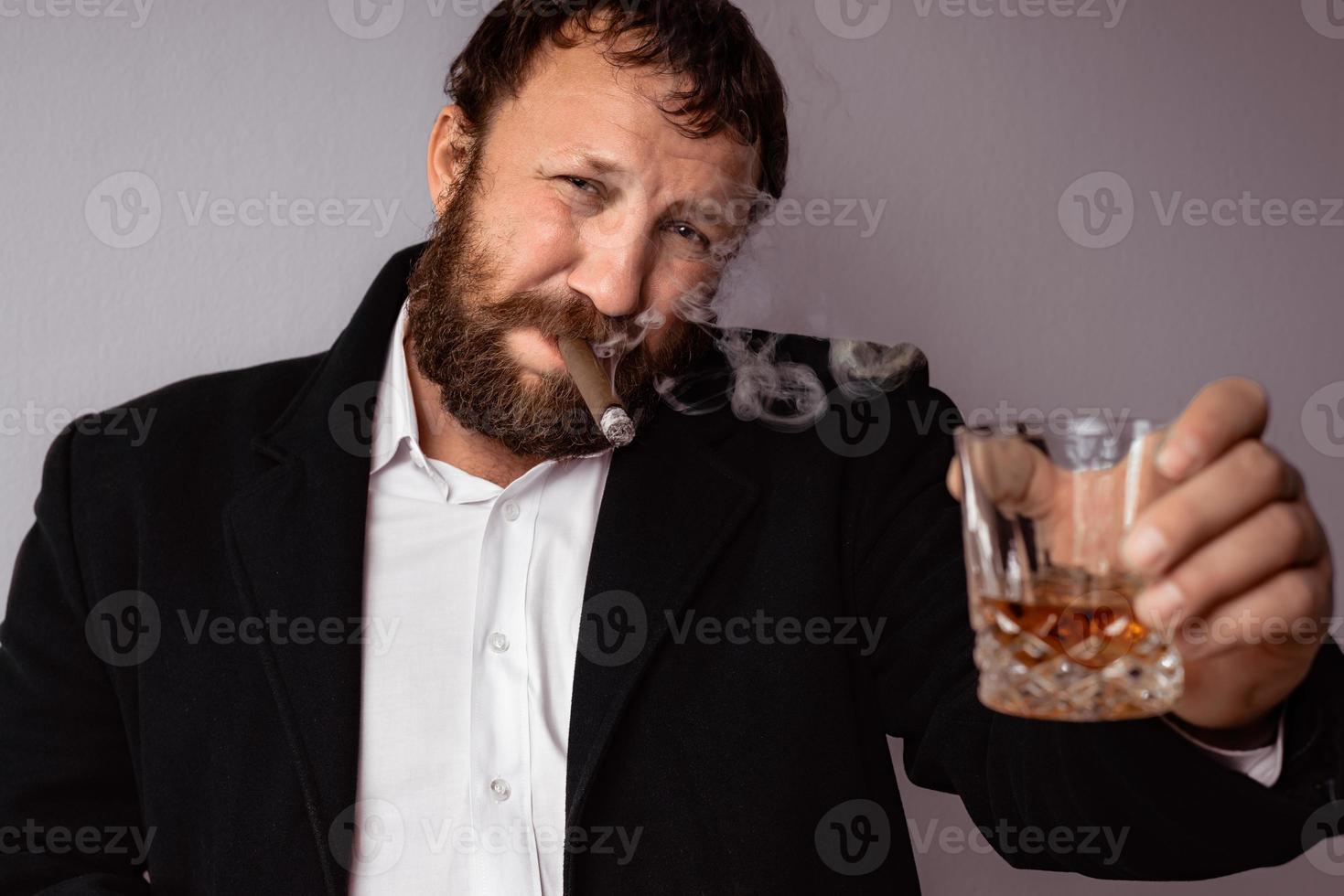 homem barbudo com casaco e camisa modernos fumando seu charuto foto