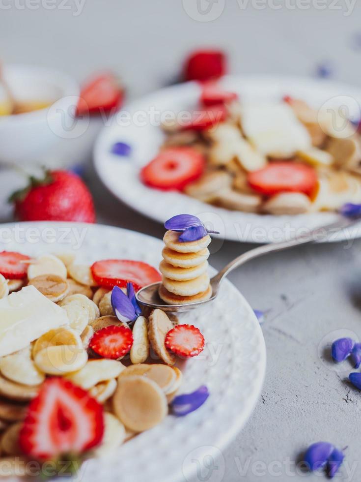 Cereais para panqueca, comida da moda. mini panquecas de cereais com manteiga, mel e morangos. foto