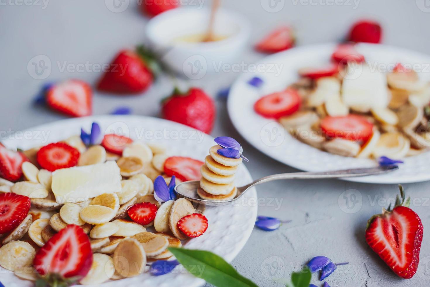 Cereais para panqueca, comida da moda. mini panquecas de cereais com manteiga, mel e morangos. foto