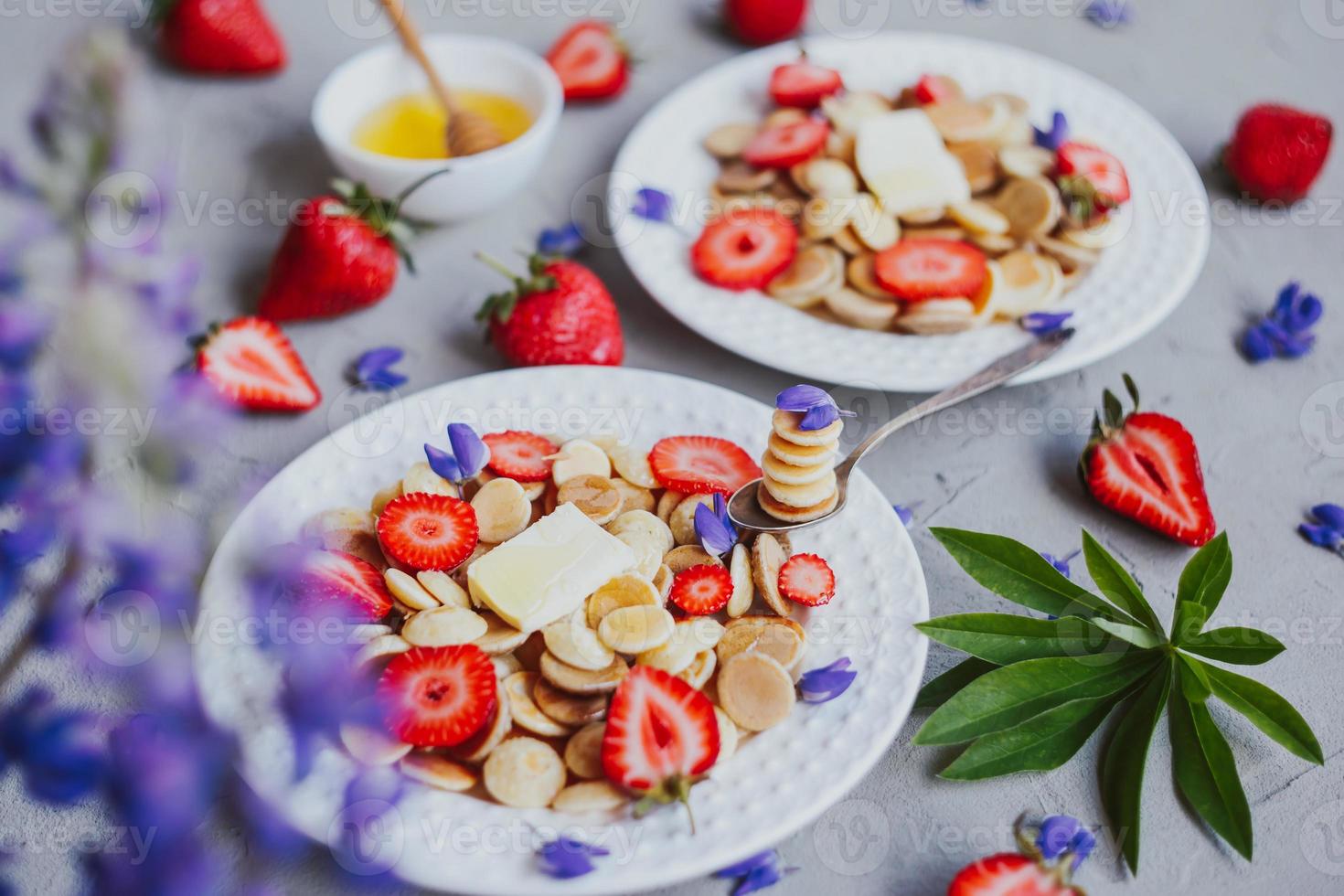 Cereais para panqueca, comida da moda. mini panquecas de cereais com manteiga, mel e morangos. foto