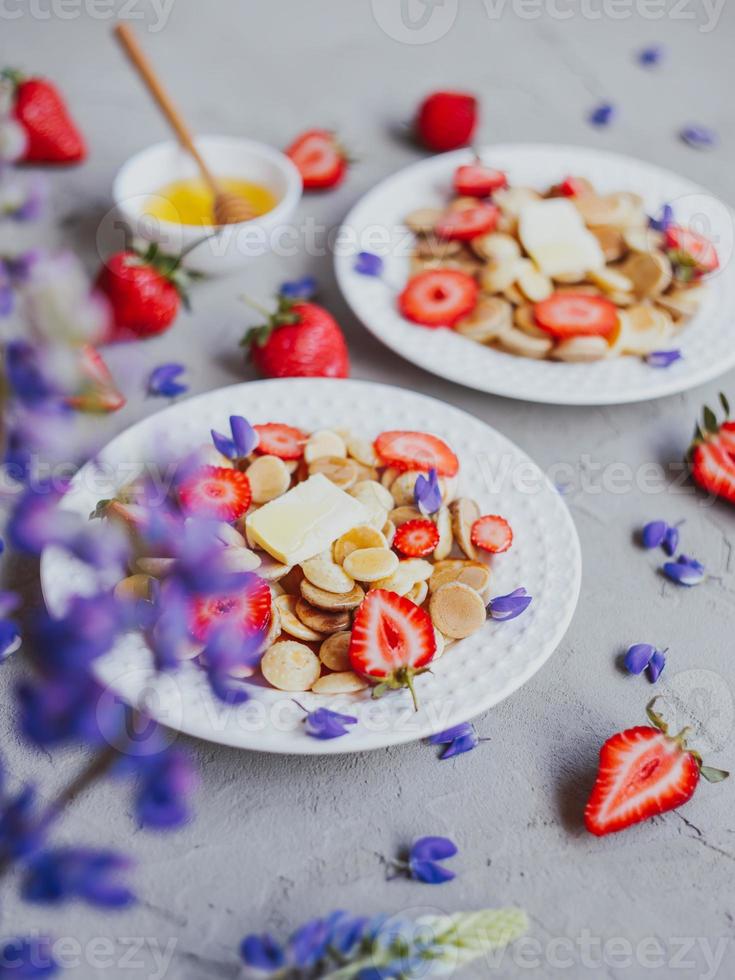 Cereais para panqueca, comida da moda. mini panquecas de cereais com manteiga, mel e morangos. foto