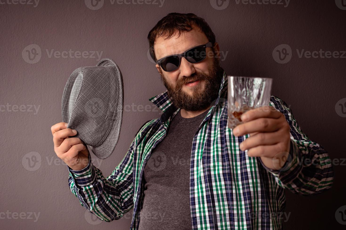 hipster bonito barbudo homem com chapéu, óculos escuros e camisa foto