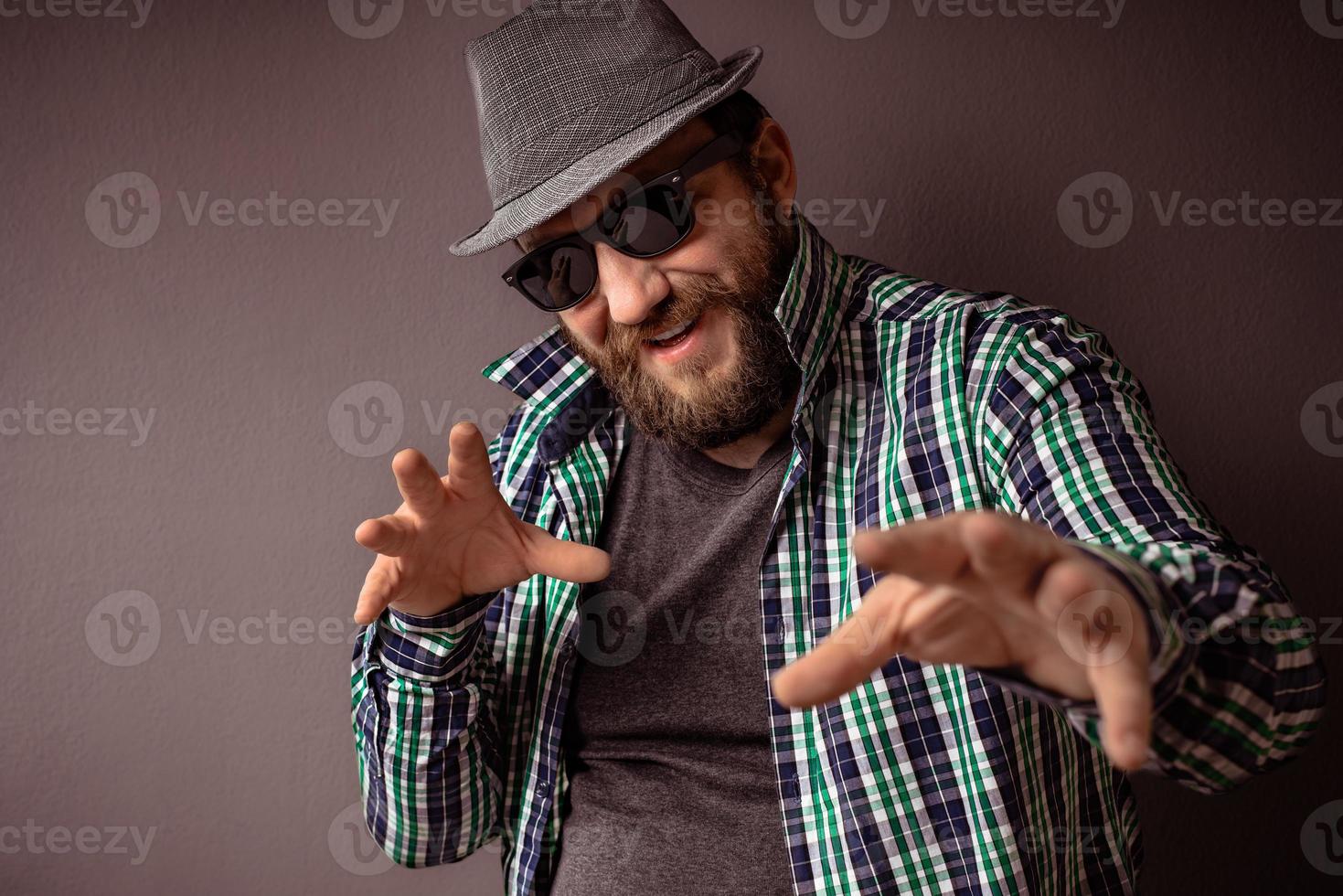 hipster bonito barbudo homem com chapéu, óculos escuros e camisa foto