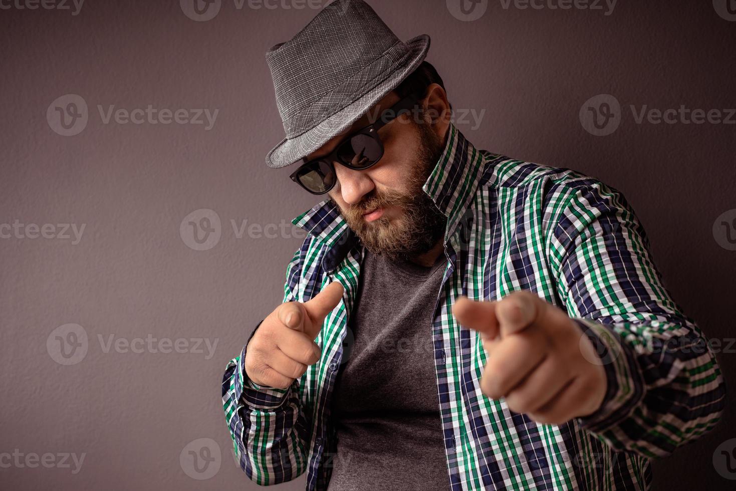 hipster bonito barbudo homem com chapéu, óculos escuros e camisa foto