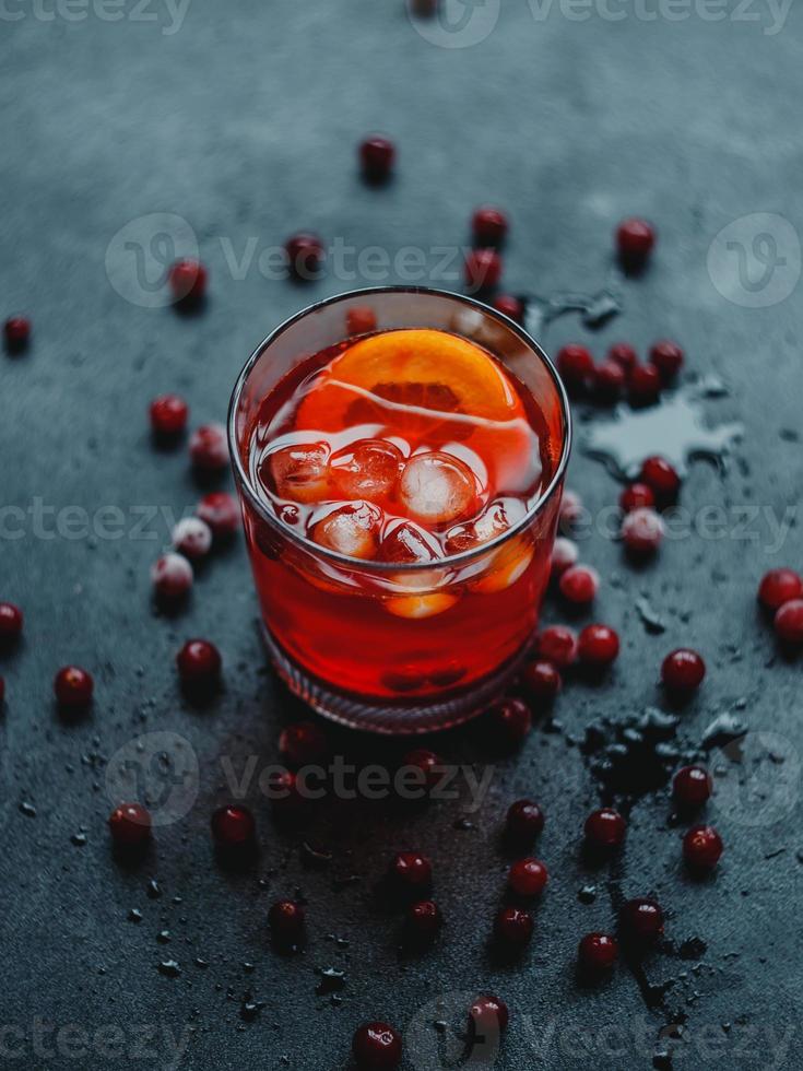 aperol spritz com gelo e cranberries em um fundo preto. foto