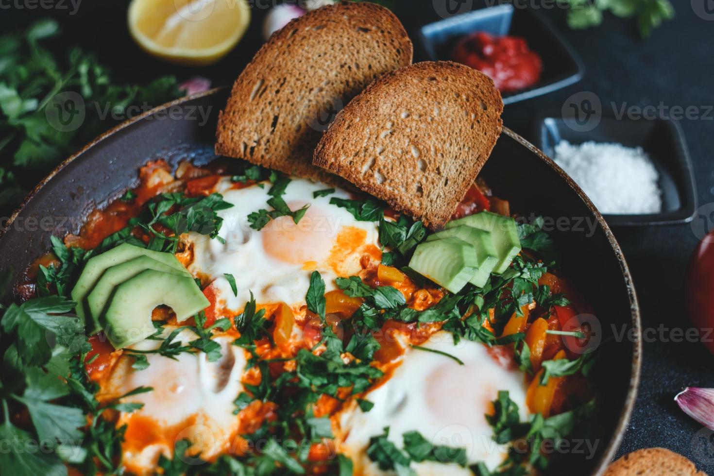 shakshuka com ovos, tomate, pimentão e salsa em uma panela. shakshuka é uma comida tradicional israelense. foto