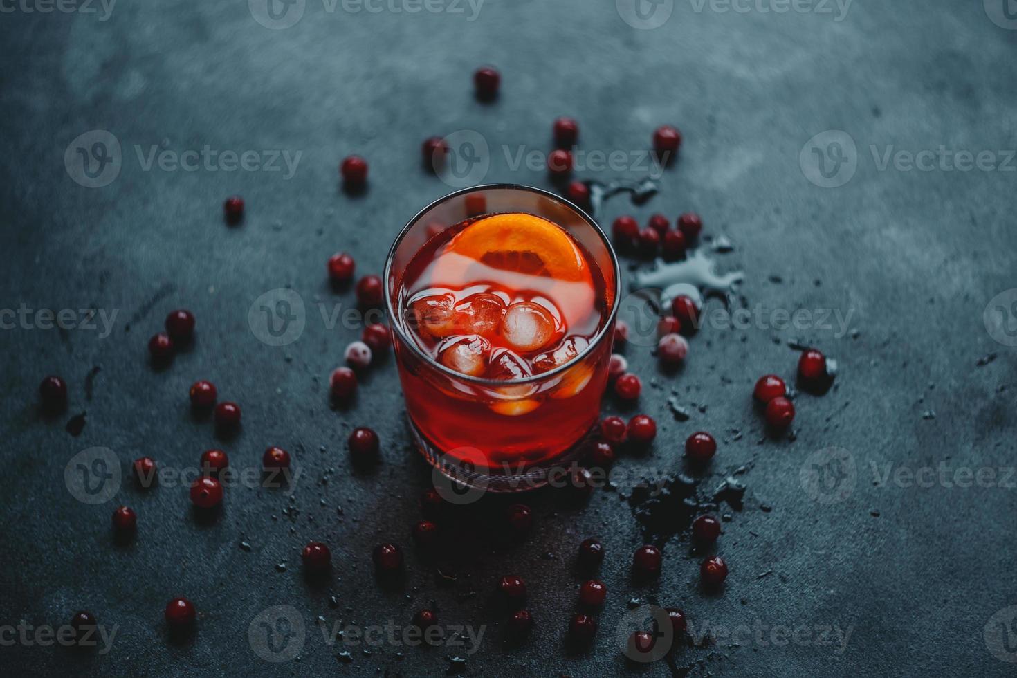 aperol spritz com gelo e cranberries em um fundo preto. foto