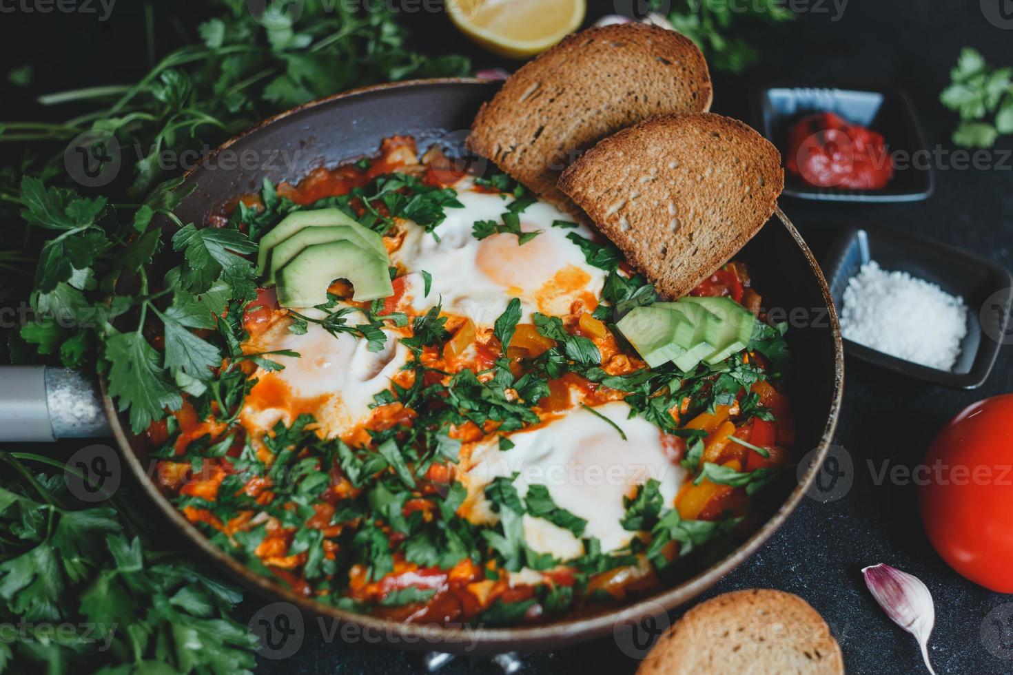 shakshuka com ovos, tomate, pimentão e salsa em uma panela. shakshuka é uma comida tradicional israelense. foto