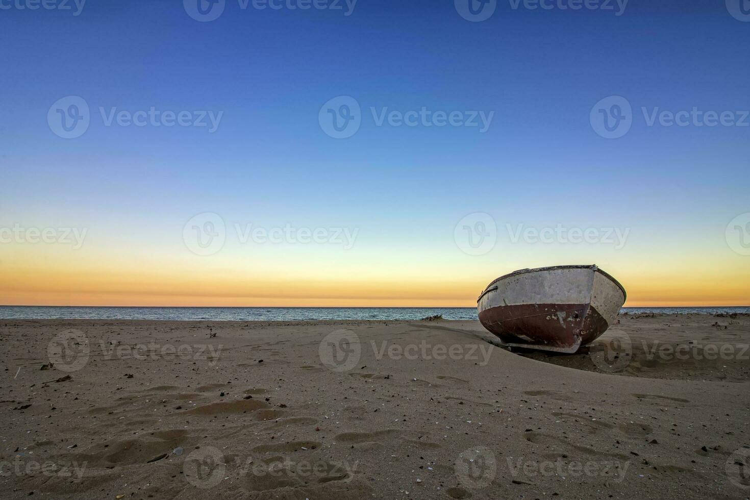 solitário velho barco em a de praia às pôr do sol. horizontal Visão foto
