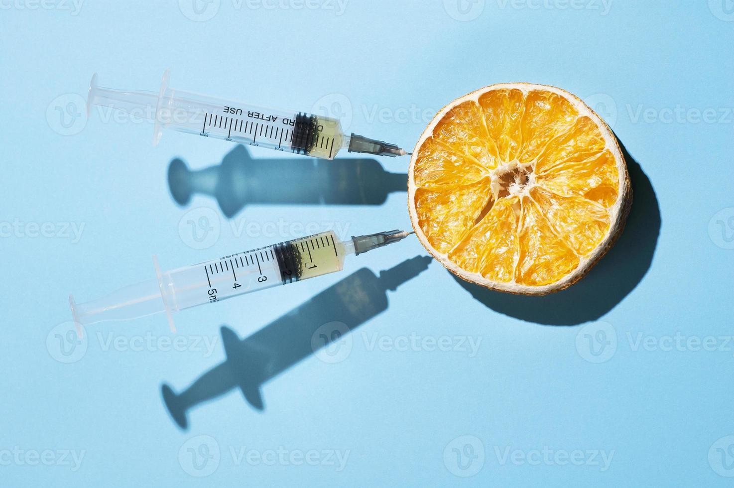 conceito mínimo com uma laranja seca e duas seringas foto