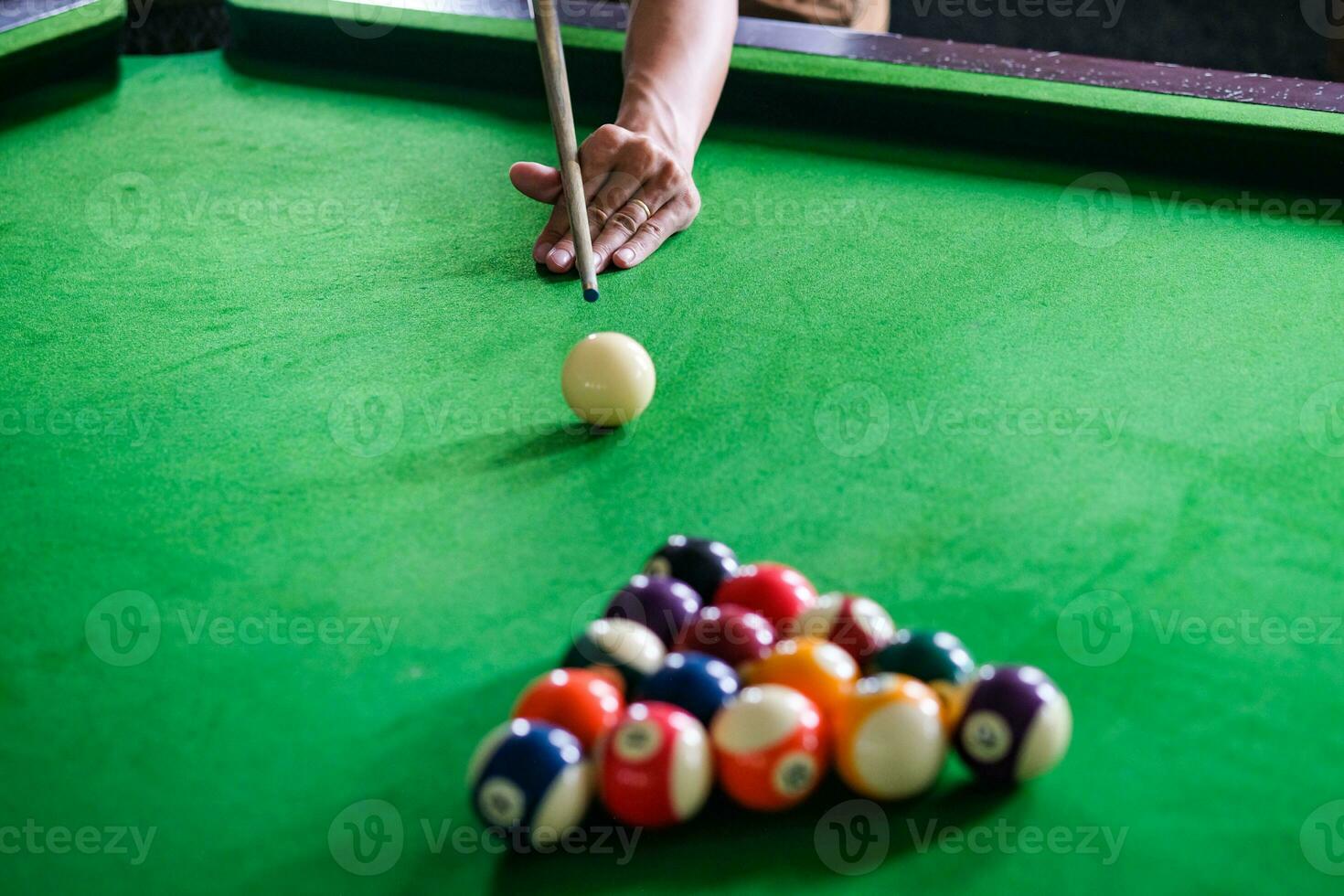 do homem mão e sugestão braço jogando sinuca jogos ou preparando visando para tiro piscina bolas em uma verde de bilhar mesa. colorida sinuca bolas em verde friso. foto