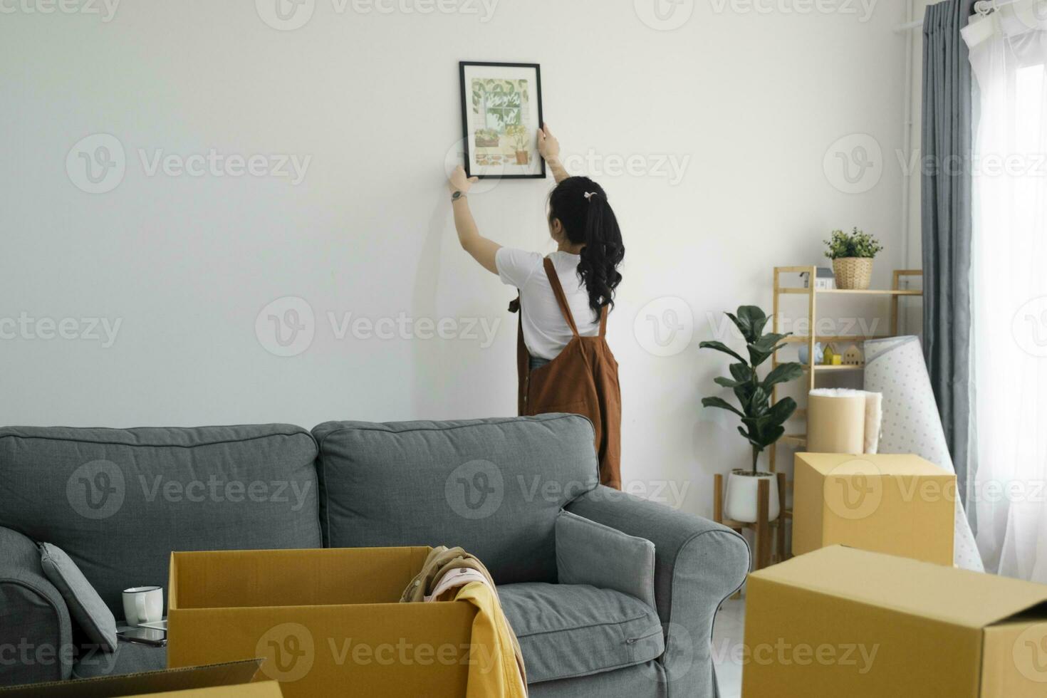 mulher decoração Novo casa enquanto comovente dentro para Novo casa ou apartamento. foto