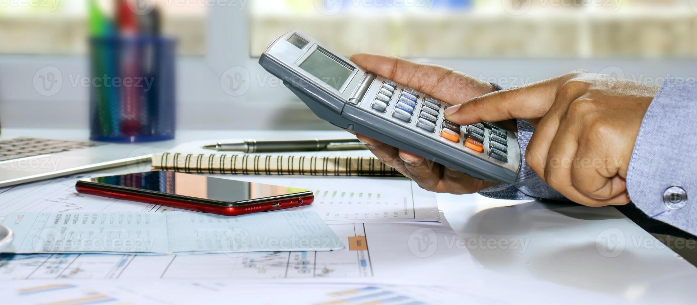 uma foto panorâmica de um homem de negócios pressionando uma calculadora e tomando notas de relatórios contábeis, conceitos de custo e economia de dinheiro.