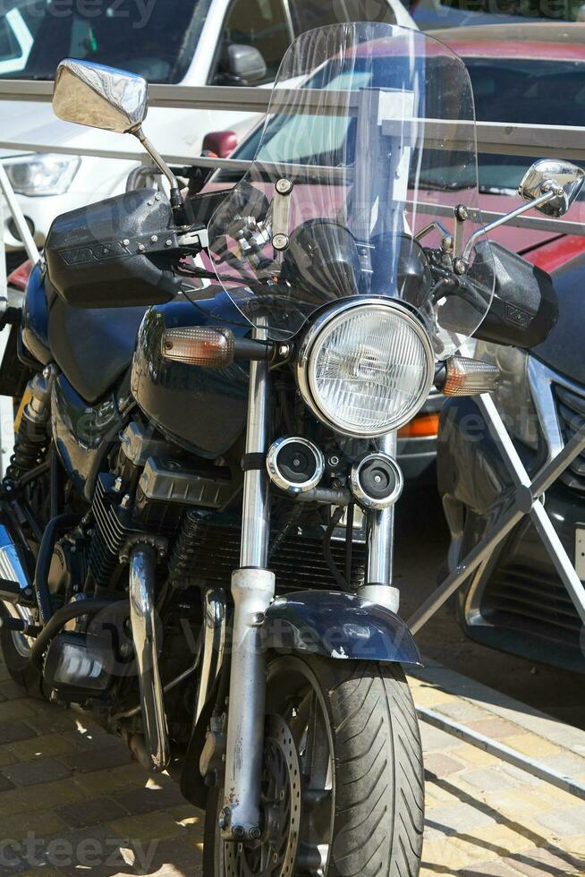 motocicleta em pé em rua contra pano de fundo estacionamento. foto