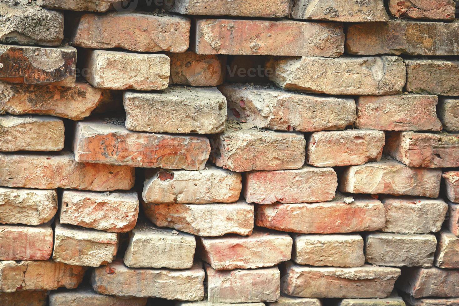 velha parede de tijolo irregular com tijolos salientes e buracos foto