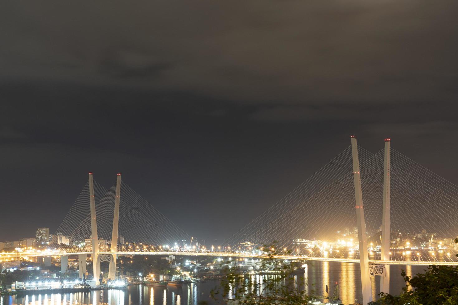 paisagem noturna da cidade com vista para a ponte dourada de vladivostok foto