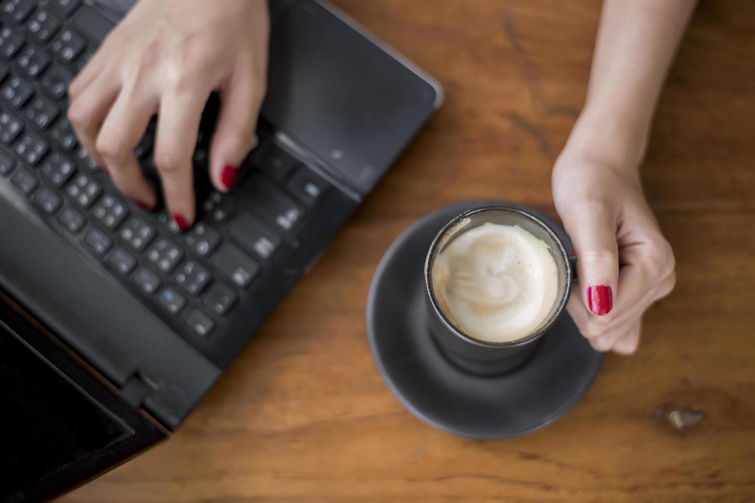 perto da mão de uma mulher segurando uma xícara de café quente na mesa de madeira foto