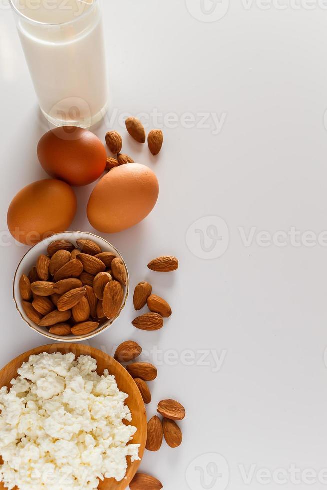 alimento proteico em um fundo branco - queijo cottage, ovos, nozes. um conjunto de alimentos saudáveis para uma alimentação equilibrada. foto