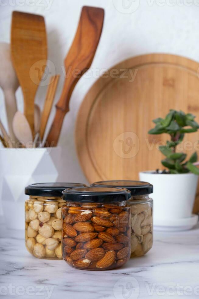 vidro frascos com querida e nozes. amêndoas, avelãs e caju dentro querida dentro cozinha interior foto