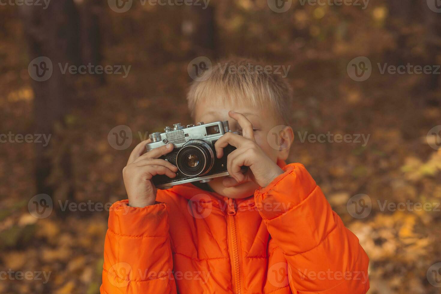 Garoto com retro Câmera levando As fotos ao ar livre dentro outono natureza. lazer e fotógrafos conceito