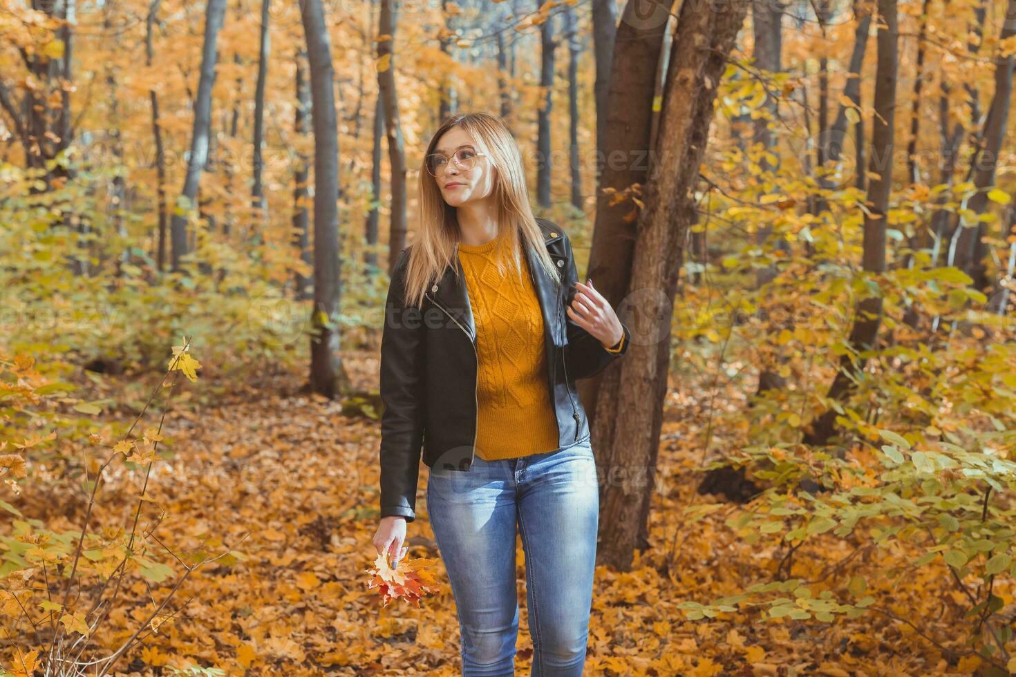 fofa risonho mulher segurando outono folhas dentro outono parque. sazonal, estilo de vida e lazer conceito. foto