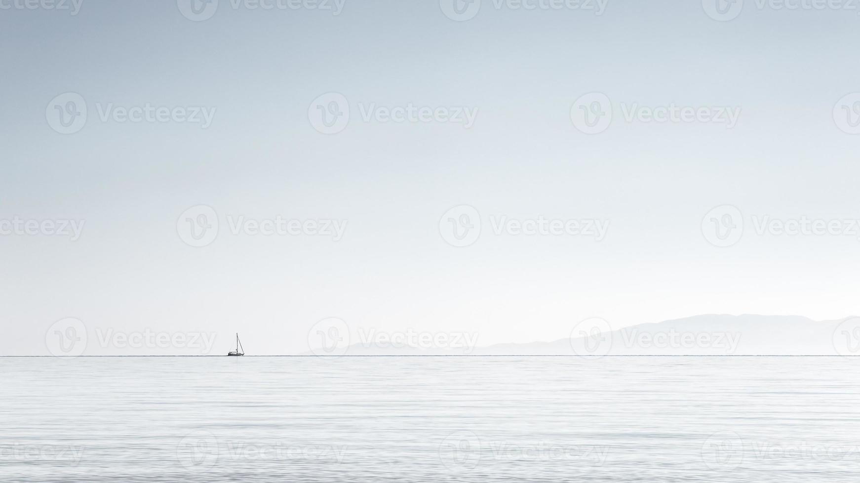 minimalismo, imagem de um pequeno barco no horizonte, céu claro no mar Egeu, halkidiki, grécia. foto