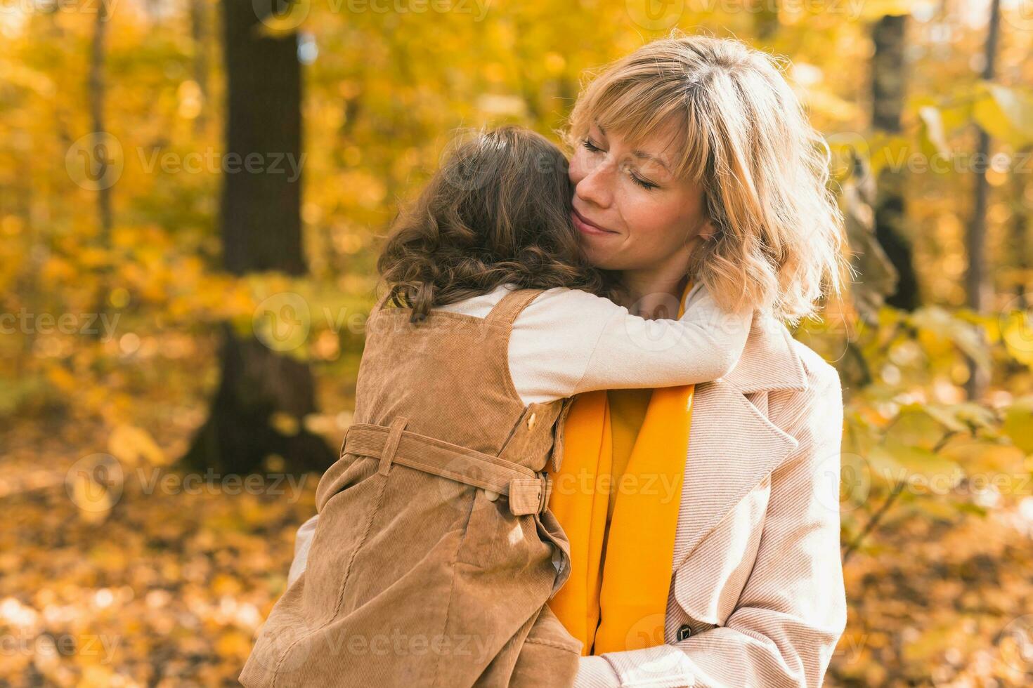 mãe com criança dentro dela braços contra fundo do outono natureza. família e estação conceito. foto