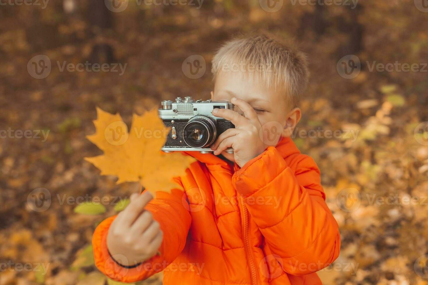 Garoto com retro Câmera levando As fotos ao ar livre dentro outono natureza. lazer e fotógrafos conceito