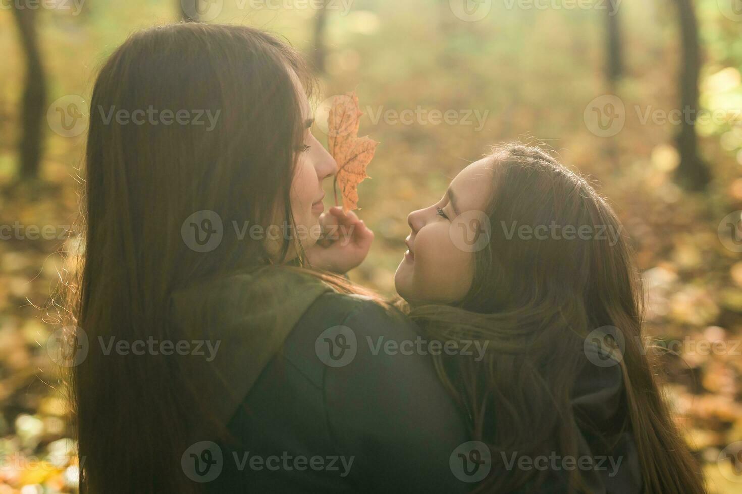pequeno menina jogando com mãe dentro a outono parque foto