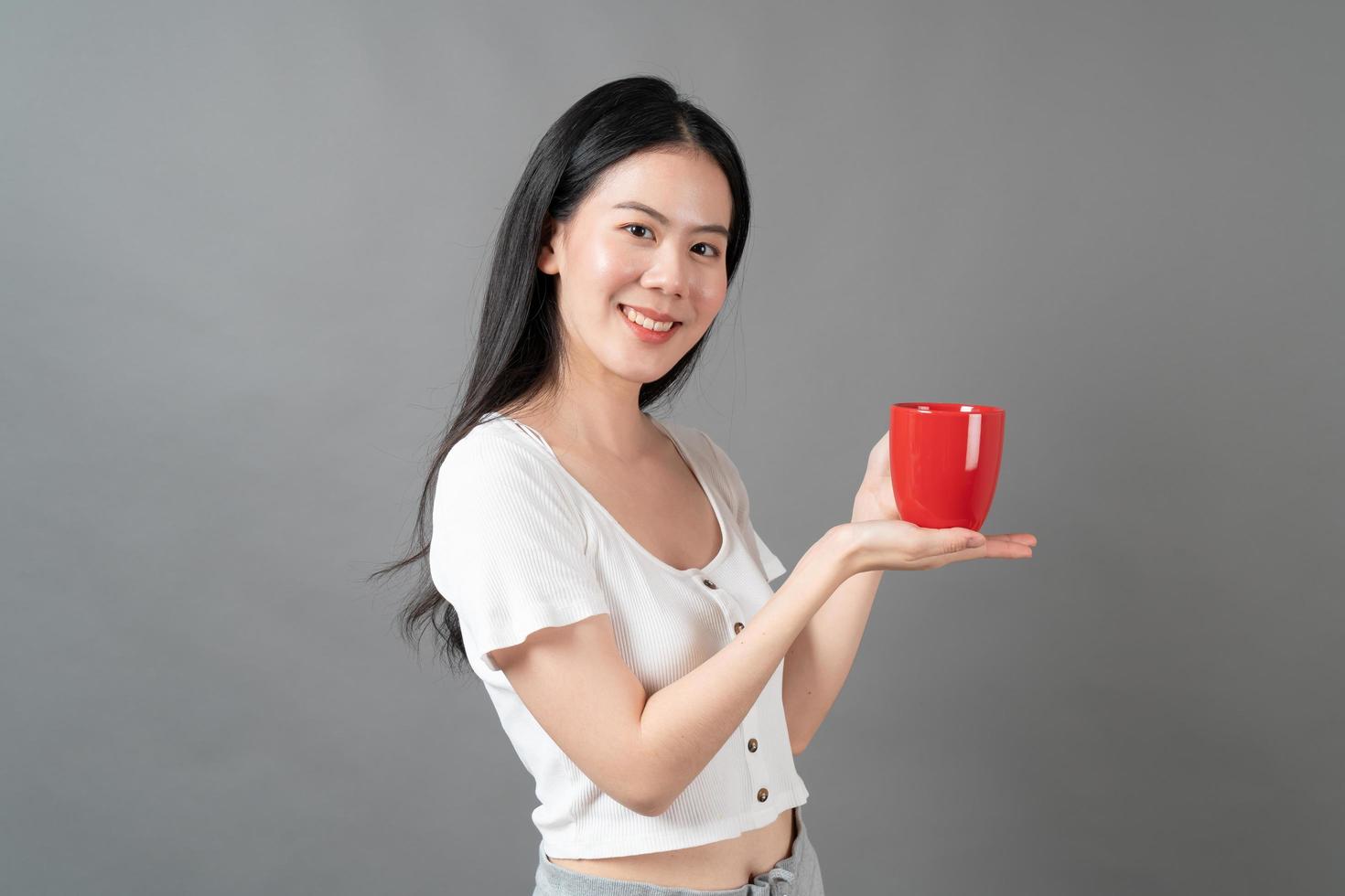 jovem mulher asiática com um rosto feliz e uma mão segurando uma xícara de café foto